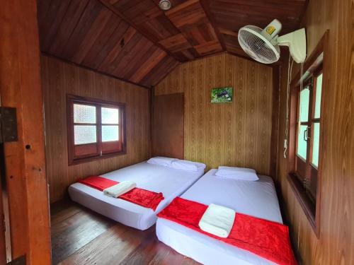 two beds in a room with wooden walls and wood floors at Khaosok Eco Raft in Ban Kraison