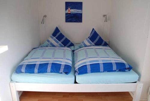 a bed with two blue and white pillows on it at Dat Ferienhus in Bad Zwischenahn