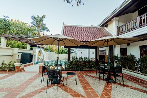 a patio with tables and chairs and umbrellas at Lux Hotel in Luang Prabang