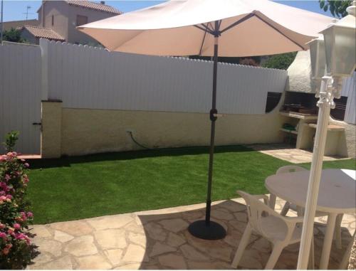 a patio with a table and an umbrella in a yard at House with pool / Garden / BBQ BEACH in Tarragona