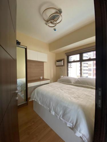 a bedroom with a white bed and a window at Le 10 The Radiance Manila Bay in Manila
