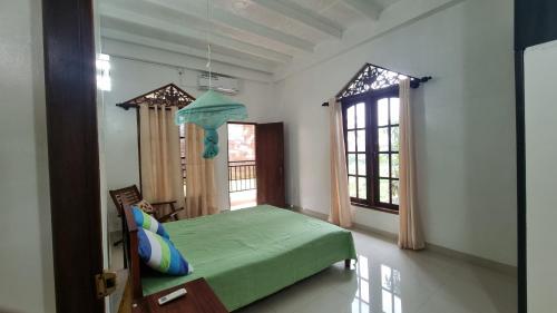 - une chambre avec un lit vert et 2 fenêtres dans l'établissement Family Tides Guest, à Kochchikade