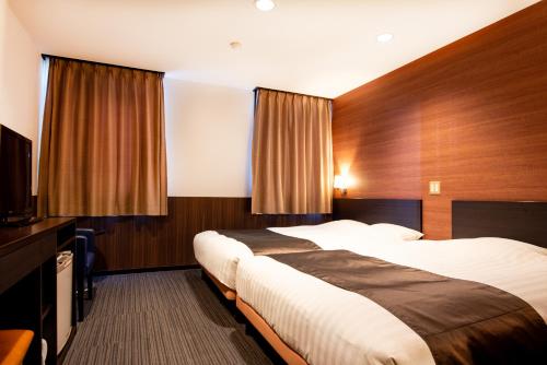 a hotel room with two beds and a flat screen tv at le Lac HOTEL Otsu Ishiyama in Otsu