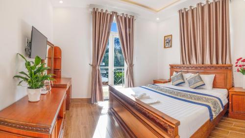a bedroom with a bed and a desk and a window at ADALY Hotel Dalat in Xuan An