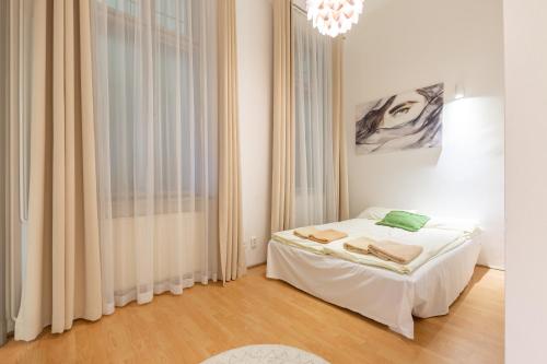 a white bedroom with a bed and a chandelier at SZ9 Szent István Apartment in Budapest