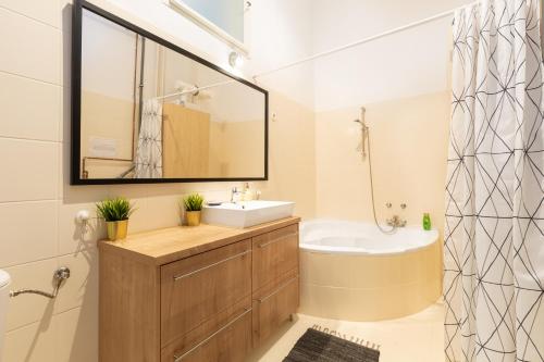 a bathroom with a sink and a tub and a mirror at SZ9 Szent István Apartment in Budapest