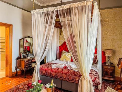 a bedroom with a canopy bed with white curtains at Betty's Boutique Hotel in Mossel Bay