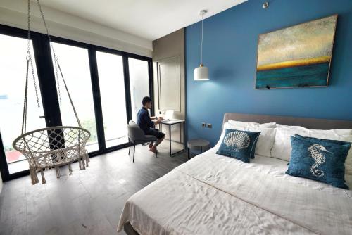 a man sitting in a chair in a bedroom with blue walls at H Hotel El Nido - Vegan Friendly Hotel Managed by H Hospitality Group in El Nido
