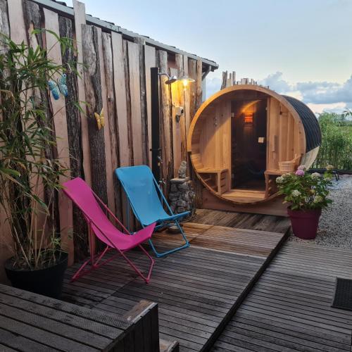 two chairs and a dog house on a deck at wellness chalet met jacuzzi, sauna, omheinde tuin, in Sint Annaland