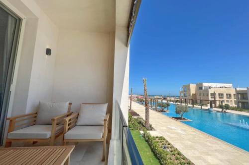 einen Balkon mit 2 Stühlen und Blick auf das Wasser in der Unterkunft Modern & Mellow 1 BDR Mangroovy Free Beach & Pool Access in Hurghada