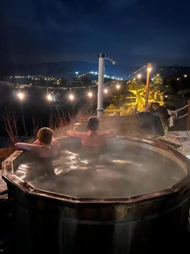 two men sitting in a hot tub at night at Osada Na Ochodzitej in Koniaków