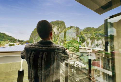 a man looking out of a window at a mountain view at H Hotel El Nido - Vegan Friendly Hotel Managed by H Hospitality Group in El Nido