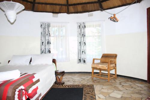 a bedroom with a bed and a chair at REED MAT LODGE in Lusaka