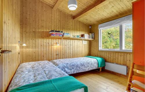 two beds in a room with wooden walls and a window at Stunning Home In Fej With 2 Bedrooms in Kragenæs