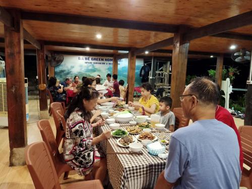 Ba Be Green Homestay في Bak Kan: مجموعة من الناس يجلسون على طاولة يأكلون الطعام