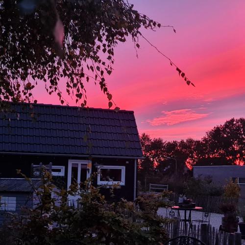 a house with a sunset in the background at wellness chalet met jacuzzi, sauna, omheinde tuin, in Sint Annaland