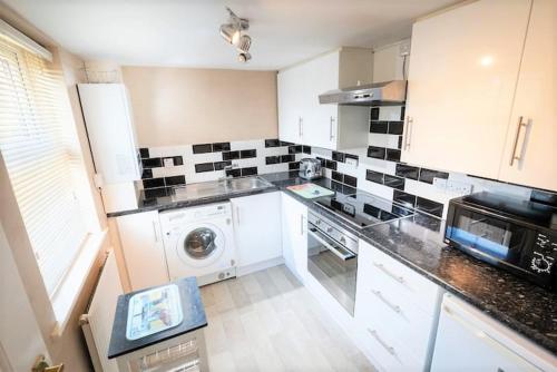 a kitchen with black and white tiles on the wall at Quiet 2 Bedroomed Cottage, near the Lakes in Carnforth