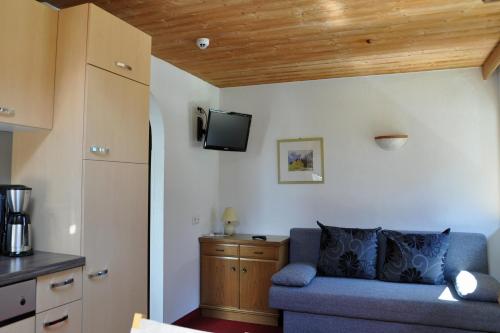 a living room with a blue couch and a tv at Apart - und Frühstückspension Jägerheim in Kaunertal