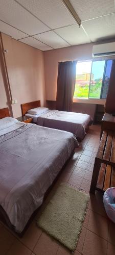 1 dormitorio con 2 camas y ventana en East Coast Hotel, en Kuantan