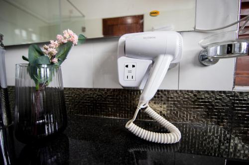a white hair dryer on a counter next to a vase at The Breeze Residence, Kottawa in Kottawa