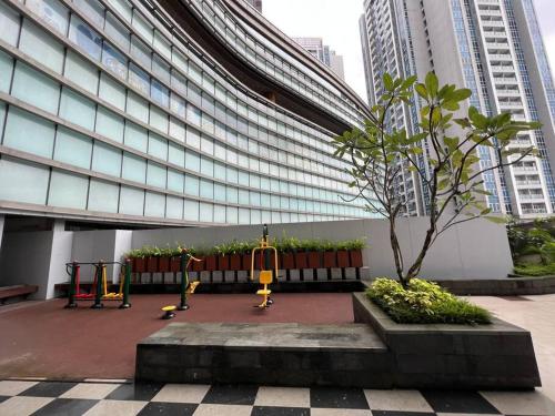 a playground in front of a building with a tree at Podomoro City Deli Medan Tower Empire - Japandi Style - 2BR Family Suite 3 beds - 87m in Medan