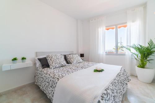 ein weißes Schlafzimmer mit einem Bett mit Blumen darauf in der Unterkunft Ideal Property Mallorca - Maritimo in Alcúdia