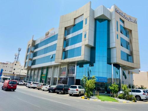 a large building with cars parked in a parking lot at راحة للأجنحة الفندقية Comfort hotel suites in Hail