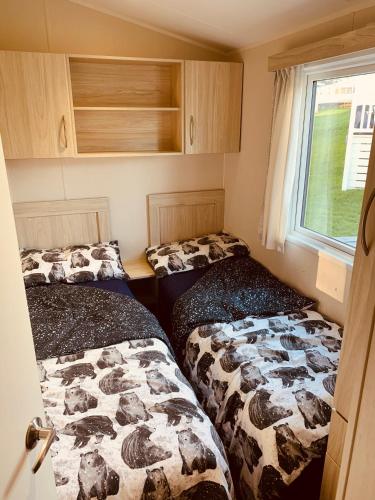 two beds in a small room with a window at 69 Newquay bay resort Pet friendly in Newquay