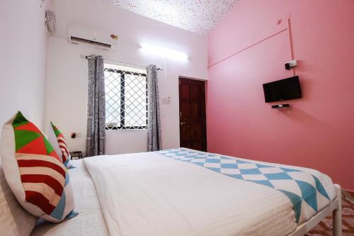 a bedroom with a bed with a pink wall at Cosmos @ Greenspace in Siolim