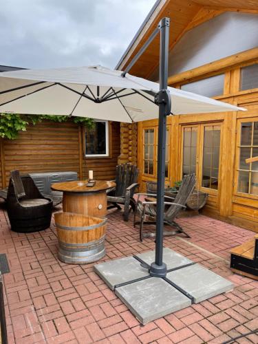 a patio with an umbrella and a table and chairs at Wellness Hütte am Zwenkauer See bei Leipzig in Zwenkau