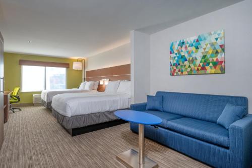 a hotel room with a bed and a blue couch at Holiday Inn Express Hotel & Suites Thornburg-S. Fredericksburg by IHG in Thornburg