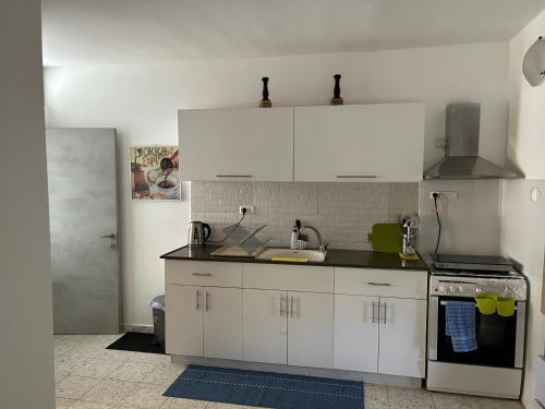 a kitchen with white cabinets and a sink at הבית בגן in Gan Yavne