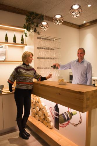 a man and a woman standing at a counter with wine glasses at Winzerhof Lentsch in Jois