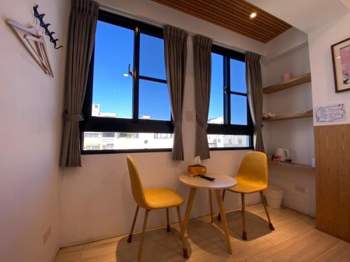uma pequena mesa e duas cadeiras num quarto com janelas em 良文旅 Ryou Hotel Tainan em Tainan