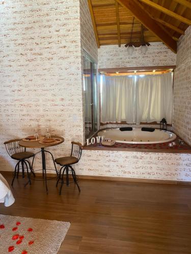 a bathroom with a tub and a table and chairs at Chale Villa do Valle in Monte Verde
