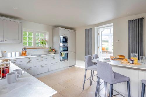 a kitchen with white cabinets and a table and chairs at Wisteria View with hottub & cabin sleeps 20 in Chippenham