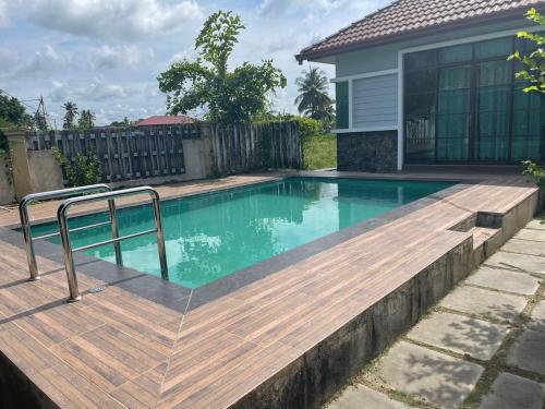 een zwembad met een houten terras naast een huis bij Alor Lanchang Roomstay in Arau