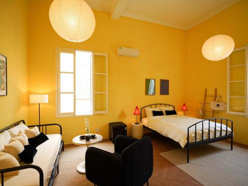 a bedroom with yellow walls and a bed and a couch at 1986 Cafe & Stay in Hai Phong