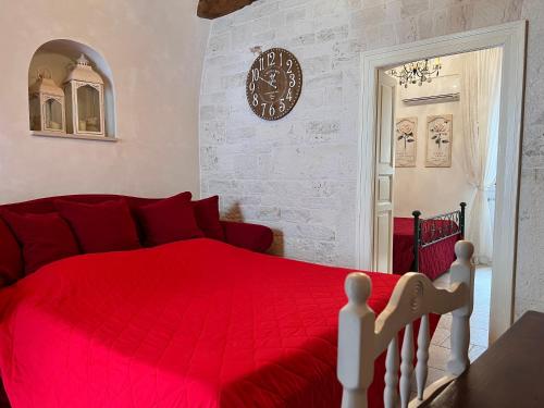 a bedroom with a red bed and a clock on the wall at Resort Romano in Trulli in Alberobello
