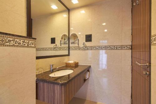 a bathroom with a sink and a large mirror at Residency Sarovar Portico in Mumbai