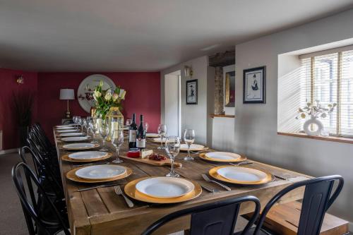 a long wooden table with chairs and wine glasses at Cotswold Way Getaway Home & Cabin Sleeps 20 in Chippenham