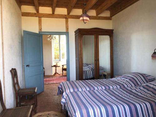 ein Schlafzimmer mit einem Bett, einem Stuhl und einem Spiegel in der Unterkunft Le Tarde - Crécerelle in Saint-Désiré