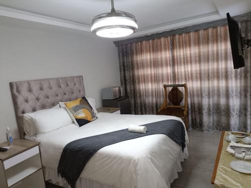 Un dormitorio con una gran cama blanca y una lámpara en EYEZULU Guesthouse, en Pinetown