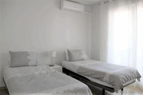 1 dormitorio blanco con 2 camas y ventana en Beautiful 2 Bed Apartment on Villamartin Plaza, en Villacosta