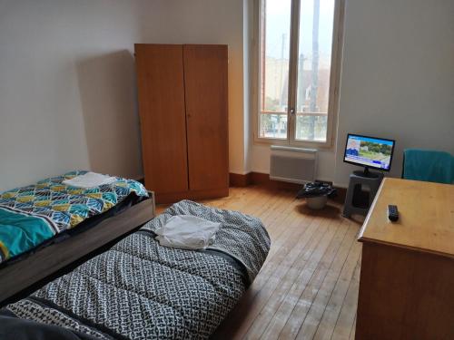 een slaapkamer met 2 bedden en een bureau met een televisie bij LOUE MAISON ENTIÈRE PROPRE ! , Endroit calme, à 5 minutes gare mantes la jolie, in Mantes-la-Jolie