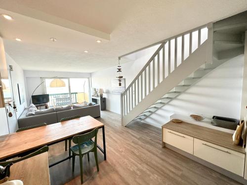 een woonkamer met een trap en een bank bij EXCEPTIONNEL ! T3 Duplex – Vue mer 180° sur le port de Lomener in Ploemeur