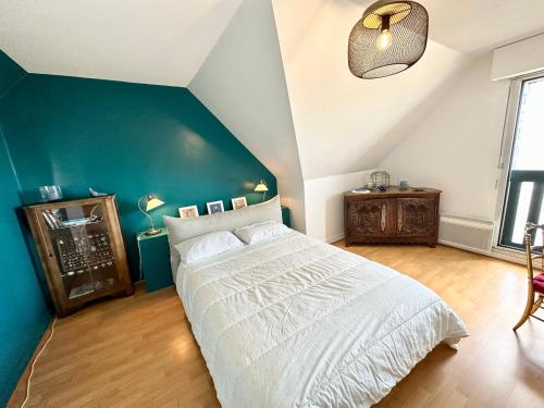 een slaapkamer met een groot bed en een blauwe muur bij EXCEPTIONNEL ! T3 Duplex – Vue mer 180° sur le port de Lomener in Ploemeur