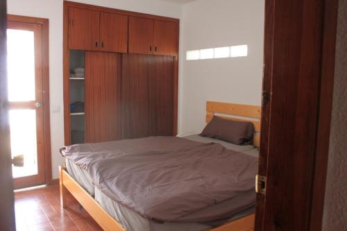 1 dormitorio con 1 cama y armario de madera en Casa Momo, en Porís de Abona