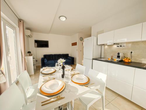 eine Küche und ein Esszimmer mit einem weißen Tisch und Stühlen in der Unterkunft Apartments - Villa Sabrina in Brela