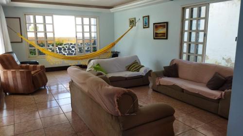 a living room with couches and a hammock at Diversão, churrasco e piscina - Praia de Ipitanga in Salvador